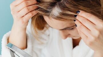 Mujer con canas mirándose al espejo