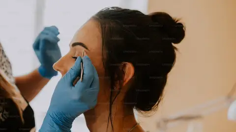 Mujer arreglando las cejas a otra Mujer arreglando las cejas a otra