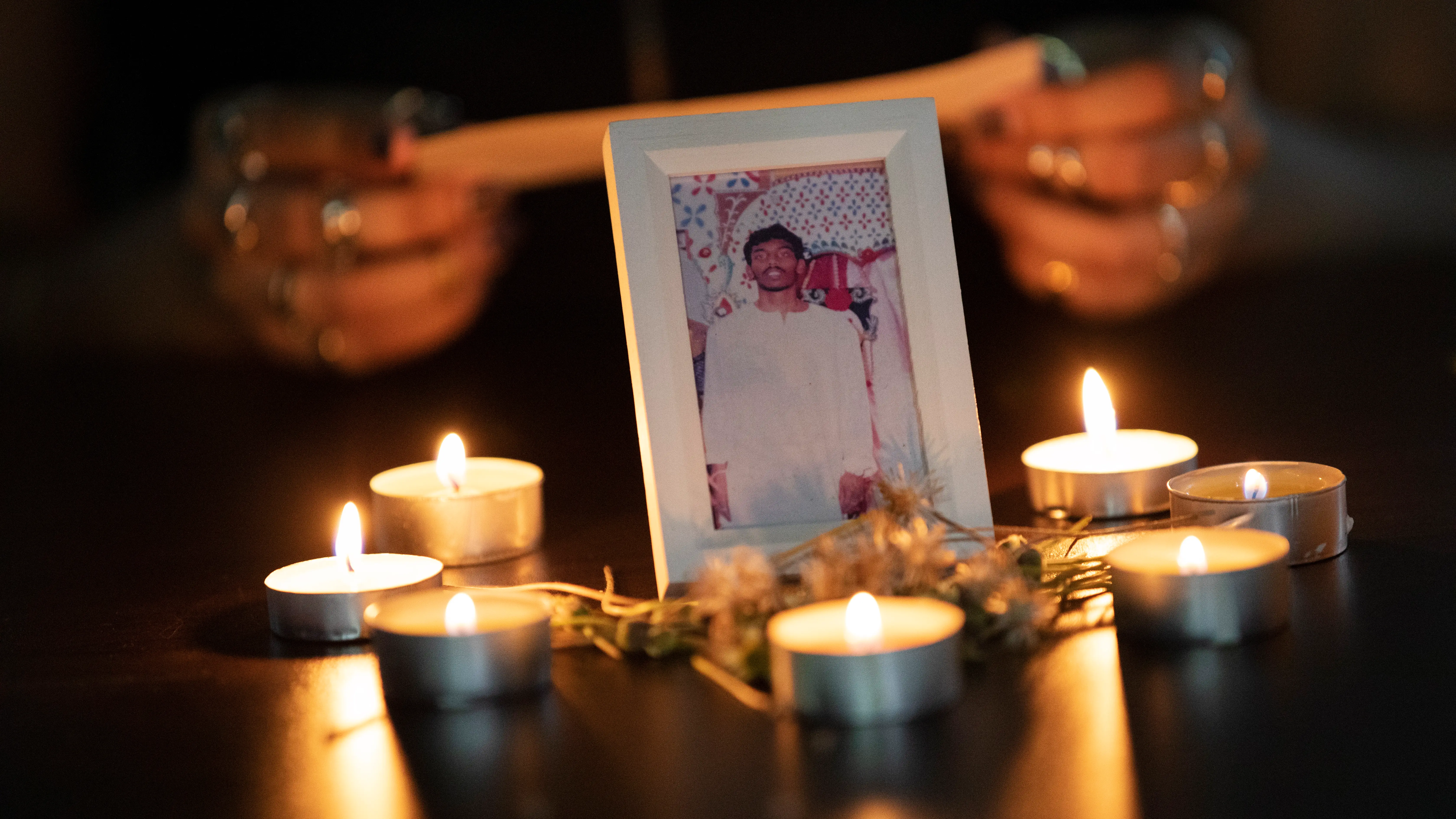 Imagen enmarcada de Tangaraju Suppiah, rodeado de velas durante una vigilia en su honor este mi&eacute;rcoles