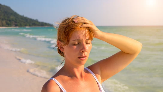 Chica en la playa con dolor de cabeza Chica en la playa con dolor de cabeza