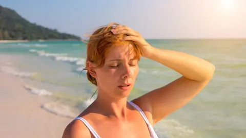 Chica en la playa con dolor de cabeza Chica en la playa con dolor de cabeza