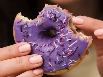Una mujer con un donut en la mano Una mujer con un donut en la mano