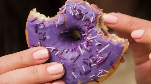 Una mujer con un donut en la mano Una mujer con un donut en la mano