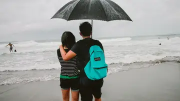 Una pareja en la playa un día de lluvia