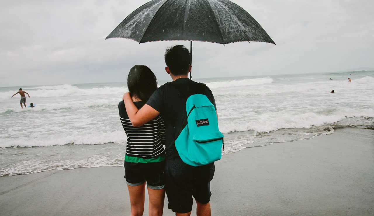 Una pareja en la playa un día de lluvia