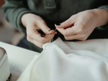 Manos de mujer arreglando una costura en una prenda de ropa