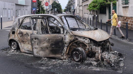 Una persona se acerca a los restos de un coche quemado en Montreuil
