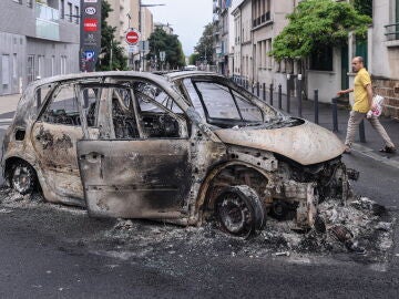 Una persona se acerca a los restos de un coche quemado en Montreuil