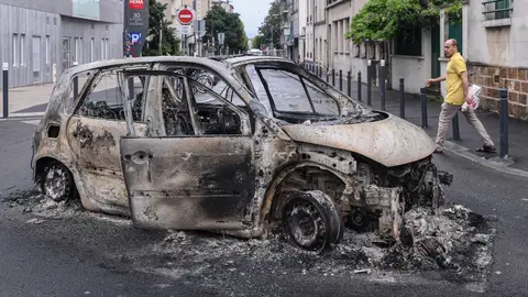 Una persona se acerca a los restos de un coche quemado en Montreuil Una persona se acerca a los restos de un coche quemado en Montreuil