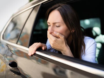 Una mujer mareada saca la cabeza por la ventanilla del coche