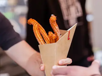 Persona sosteniendo un paquete de churros Persona sosteniendo un paquete de churros