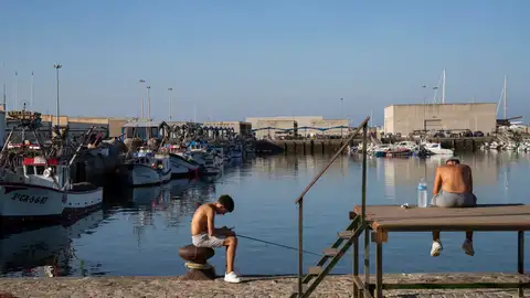 Jóvenes pescan en el muelle pesquero de Barbate, en Cádiz