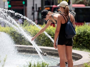 Dos jóvenes se refrescan en una fuente en Valencia
