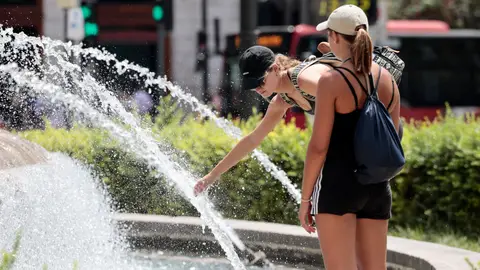 Dos jóvenes se refrescan en una fuente en Valencia Dos jóvenes se refrescan en una fuente en Valencia