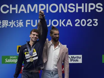 Michael Phelps levanta la mano del medallista de oro Léon Marchand Michael Phelps levanta la mano del medallista de oro Léon Marchand