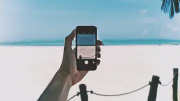 Persona grabando una playa con el teléfono móvil