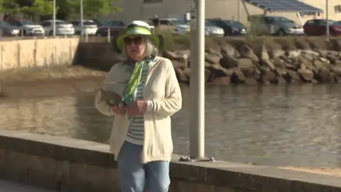 Una mujer pasea por una playa gallega Una mujer pasea por una playa gallega