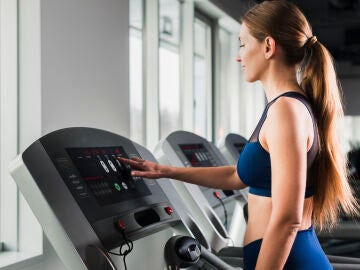 Un mujer configura su cinta de correr en un gimnasio