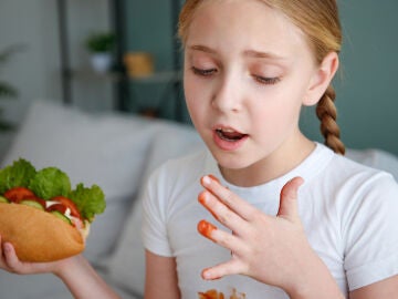 Una niña se come un bocadillo