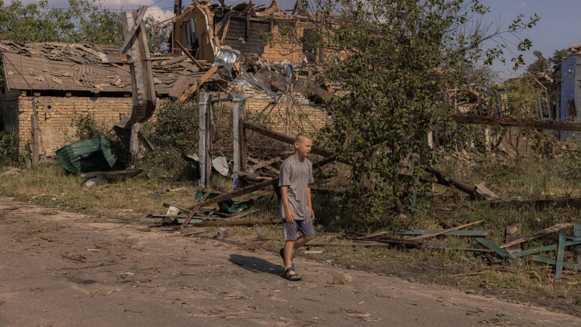 Un niño camina solo junto a los restos de casas bombardeadas en Ucrania