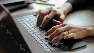 Una mujer tecleando en un ordenador