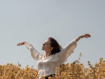 Mujer sintiendo el viento entre las flores del campo