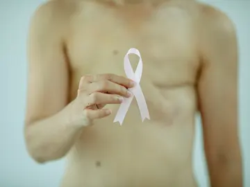 Mujer a la que le han realizado una mastectomía sujeta un lazo rosa Mujer a la que le han realizado una mastectomía sujeta un lazo rosa