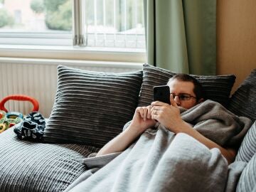 Hombre acostado en un sofá mientras mira el teléfono