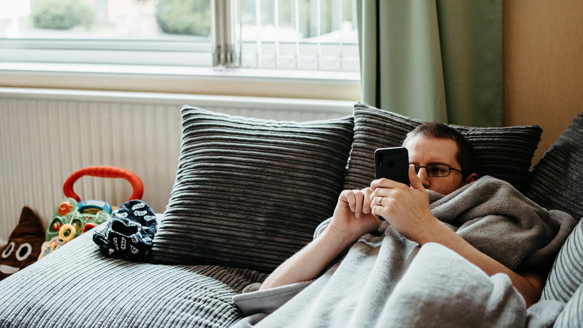 Hombre acostado en un sofá mientras mira el teléfono