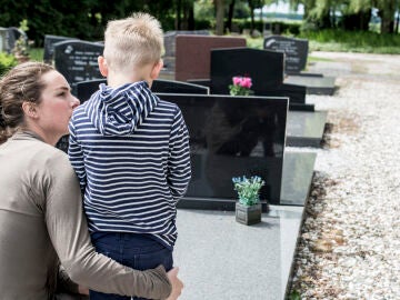 Una madre con su hijo pequeño en el cementerio