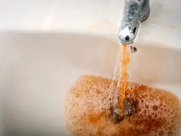 Imagen de archivo de agua sucia saliendo de un grifo Imagen de archivo de agua sucia saliendo de un grifo