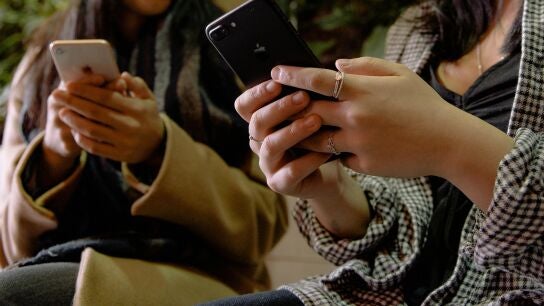 J&oacute;venes mirando sus tel&eacute;fonos m&oacute;viles