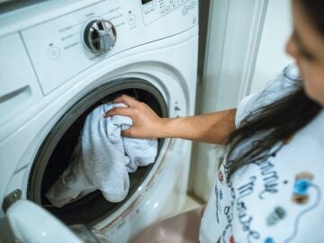 Una mujer introduce una prenda de ropa en la lavadora
