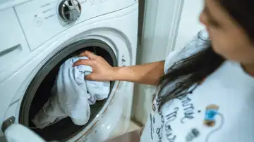 Una mujer introduce una prenda de ropa en la lavadora