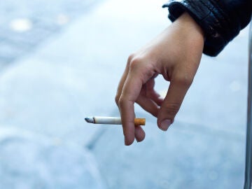 Imagen de la mano de una mujer con un cigarrillo en la calle