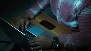Un hombre delante de un ordenador a oscuras