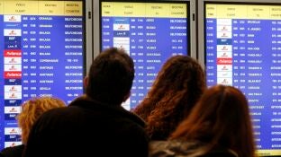 Imagen de archivo de varios viajeros consultando un panel informativo con el estado de vuelos en el aeropuerto Adolfo Su&aacute;rez-Madrid Barajas.