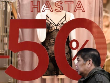 Un escaparate anuncia rebajas de hasta el 50% en una tienda del centro de Madrid este domingo