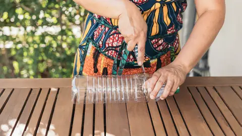 Mujer cortando una botella de plástico Mujer cortando una botella de plástico
