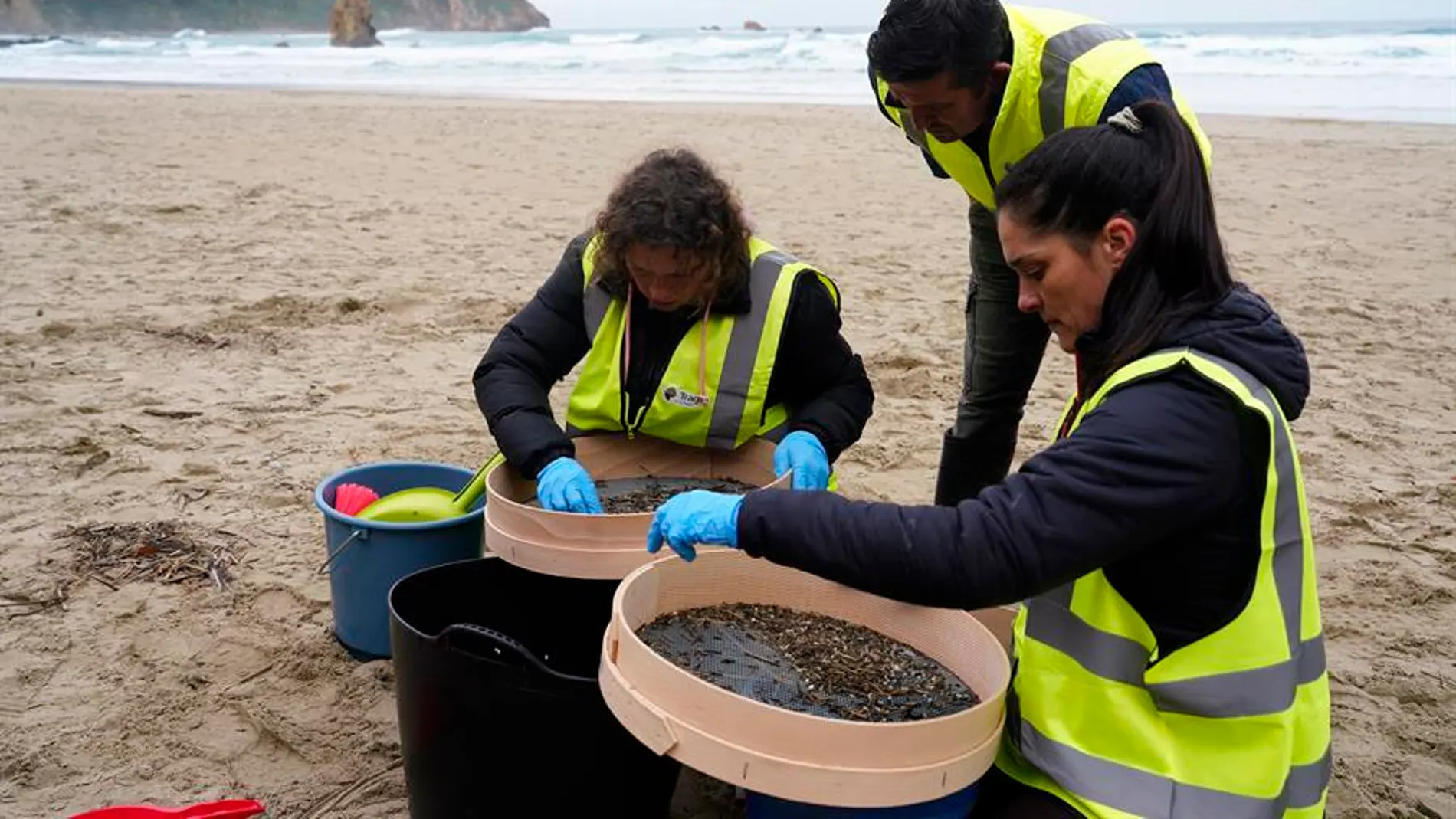 Operarios de Asturias retiran pellets de una de las playas del Principado.