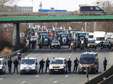 Agentes de policía vigilan decenas de tractores que participan en una manifestación en la autopista A15 cerca de Argenteuil, al norte de París, Francia