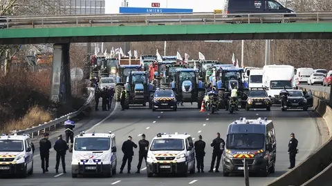 Agentes de policía vigilan decenas de tractores que participan en una manifestación en la autopista A15 cerca de Argenteuil, al norte de París, Francia