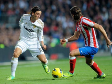 Mesut Özil controla un balón ante Filipe Luis en un Real Madrid - Atlético 