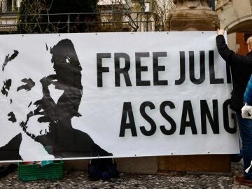 Manifestante sujeta una pancarta con el retrato de Julian Assange