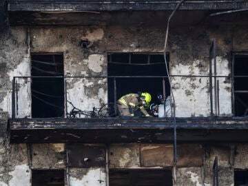 Bomberos y Policía Científica inspeccionan un cuerpo en un balcón del edificio incendiado en el barrio de Campanar de Valencia 