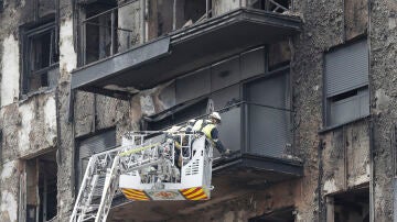 Unos bomberos trabajan en el saneamiento de la fachada del edificio siniestrado en la zona del barrio valenciano de Campanar