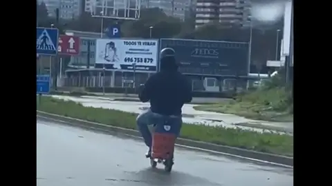 Un hombre transporta una bombona de butano en un patinete Un hombre transporta una bombona de butano en un patinete