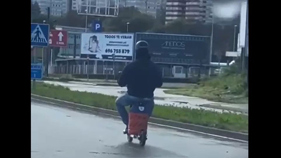 Un hombre transporta una bombona de butano en un patinete Un hombre transporta una bombona de butano en un patinete