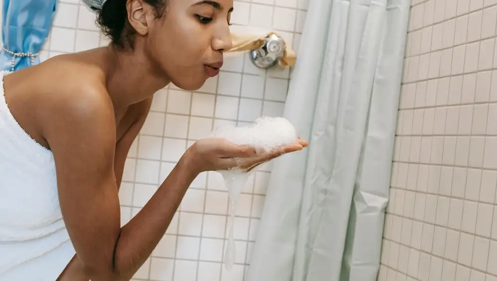 Una mujer en la ducha con jabón en la mano
