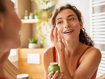 Mujer aplicándose crema en la cara Mujer aplicándose crema en la cara